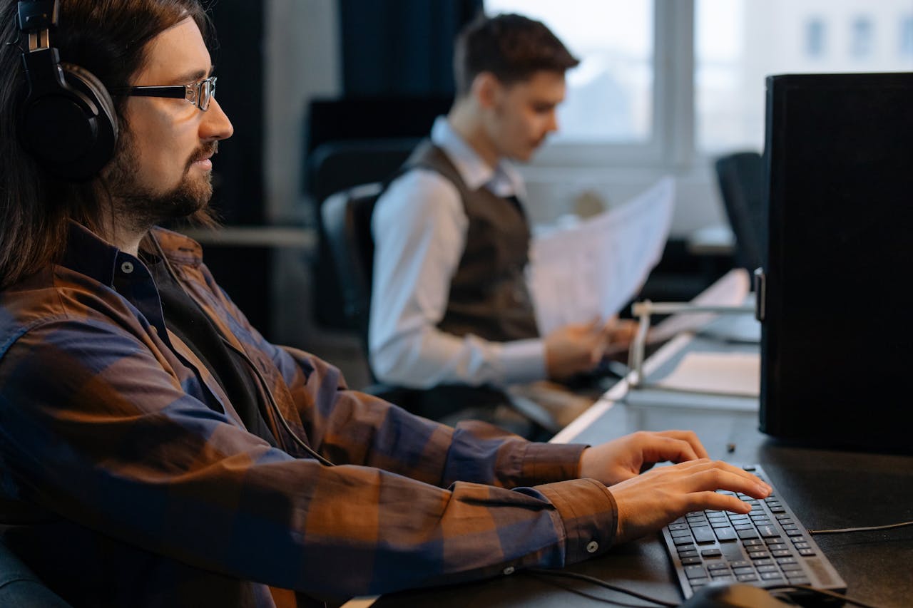 Men Sitting at the Desks in an Office and Using Computers 